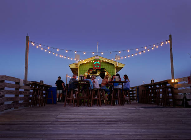People enjoying drinks at the outdoor tiki bar at the Ocean Grill restaurant in Carolina Beach, North Carolina Carolina Beach, NC - USA - 09-26-2021: People enjoying drinks at the outdoor tiki bar at the Ocean Grill restaurant in Carolina Beach NC wilmington north carolina stock pictures, royalty-free photos & images