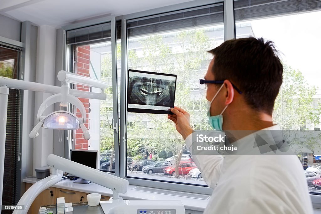 Dentista esaminando una radiografia è di denti - Foto stock royalty-free di Adulto