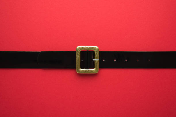 Creative Christmas composition. Overhead flat lay view photo of Santa Claus black belt with golden buckle on bright color red backdrop Creative Christmas composition. Overhead flat lay view photo of Santa Claus black belt with golden buckle on bright color red backdrop belt stock pictures, royalty-free photos & images