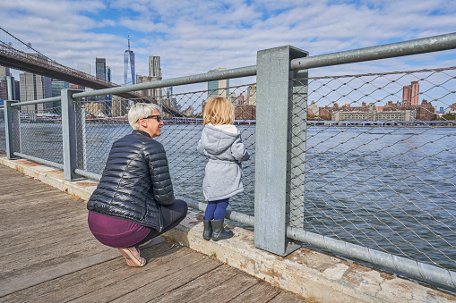Mother and Toddler enjoying  Empire Fulton Ferry with a view of the Brooklyn Bridge and downtown Manhattan skyline as Seen from the DUMBO Area of Brooklyn New York City