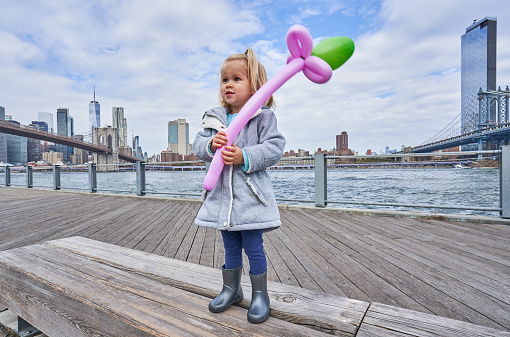 Toddler enjoying  Empire Fulton Ferry with a view of the Brooklyn Bridge and downtown Manhattan skyline as Seen from the DUMBO Area of Brooklyn New York City