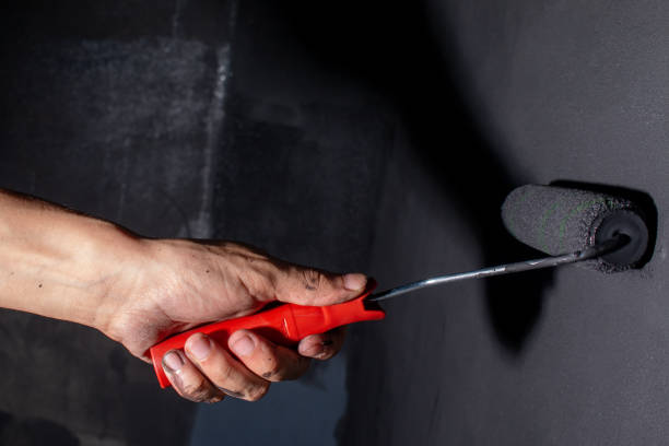istock Brown hand painting a black wall. Concept of workmanship work. 1351547375