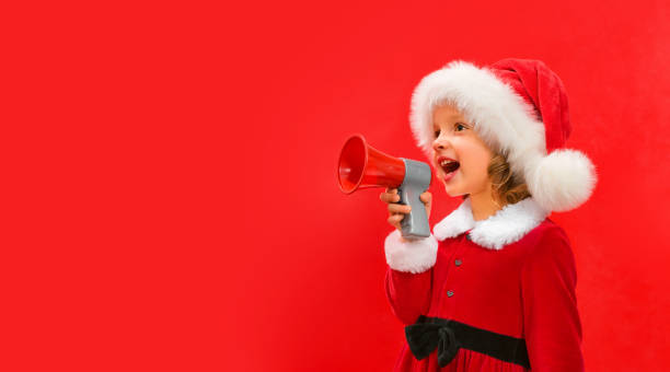 빨간 산타 모자를 쓴 한 어린이가 메가폰을 손에 들고 �소리쳤다. 크리스마스와 새해 슬로건을 위한 컨셉 - surprise shouting child black and white 뉴스 사진 이미지