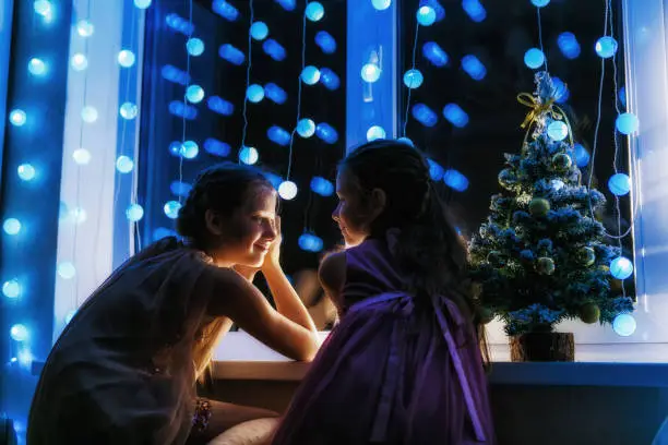On Christmas night, the sisters look at each other by the window, waiting for Santa Claus.