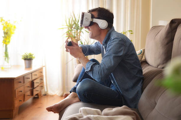istock Entertaining man playing in virtual reality glasses at home 1351553303