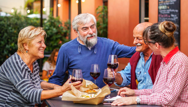 felices amigos ancianos bebiendovino durante la cena - discussion talking italy usa fotografías e imágenes de stock