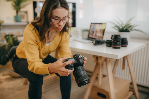 Female photographer using and testing out her new camera, while working in her studio.