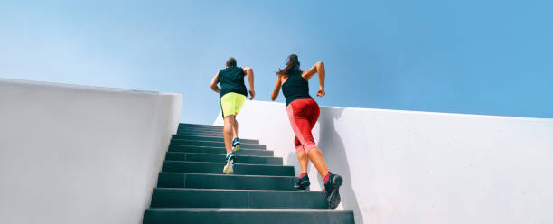 Stairs runners running up training hiit workout banner. Couple athletes sprinting uphill working out dynamic exercise panoramic. stock photo