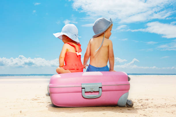 istock Two children sit on suitcase at the beach concept 1351574115