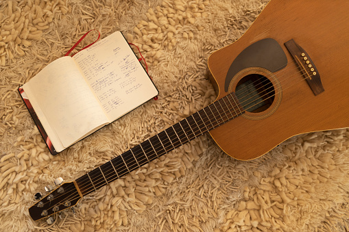 Dark wooden guitar and composition notebook with written letters
