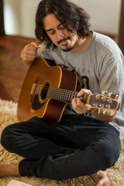 istock Man playing guitar at home 1351575208