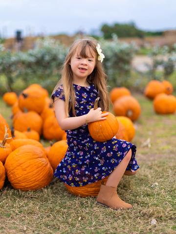 Happy cuban american girl sitting on a pumpkin in a patch