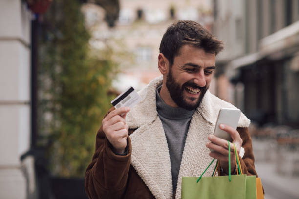 istock A smiling young man is carrying shopping bags, while he submits an order for goods that he ordered online. 1351580455