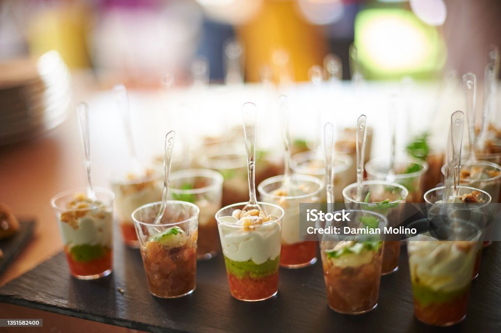 Fruit desserts served in cups Assorted fruit parfait desserts served in plastic cups with spoons during banquet in restaurant Parfait Stock Photo