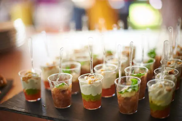 Assorted fruit parfait desserts served in plastic cups with spoons during banquet in restaurant