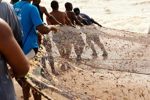 Salvador, Bahia, Brazil - January 11, 2019: Fishermen pulling their fishing net out of the sea.