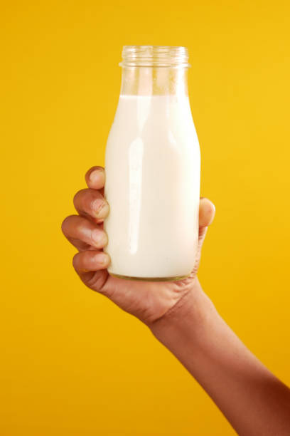istock hand hold a milk bottle against yellow background 1351590787