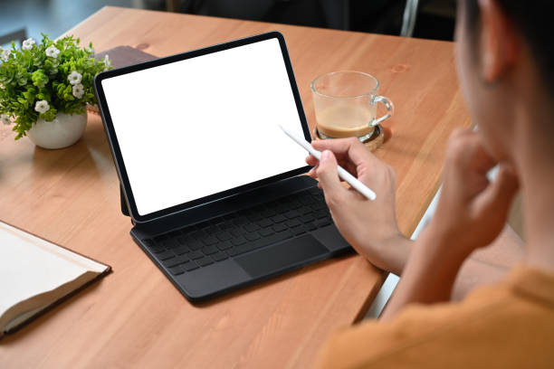 istock View over shoulder young man using computer tablet on wooden desk. 1351600125