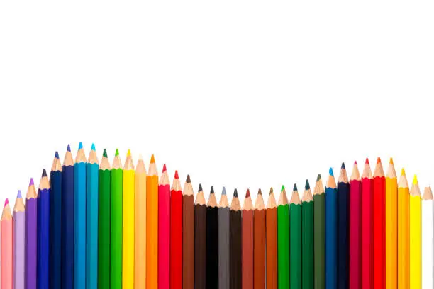 Closeup of coloured pencils lined up in a row on white background with copy space