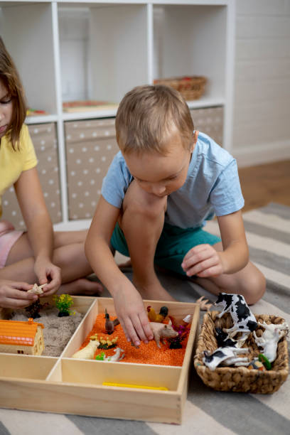 istock Touch drawer with rainbow rice inside. Children hand touch the texture. Montessori material concept for toddlers. 1351603599
