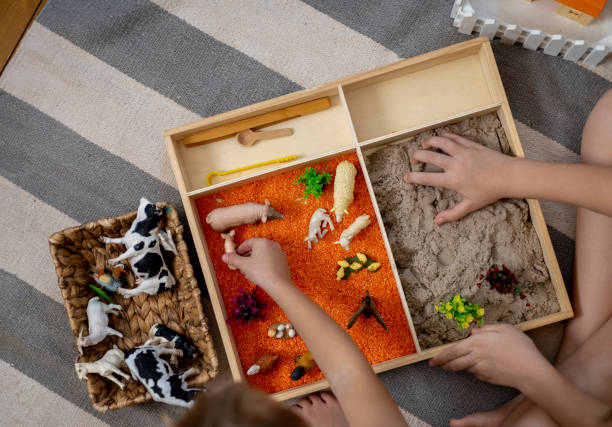 istock Touch drawer with rainbow rice inside. Children hand touch the texture. Montessori material concept for toddlers. 1351603619