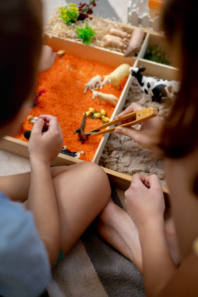 istock Touch drawer with rainbow rice inside. Children hand touch the texture. Montessori material concept for toddlers. 1351603773