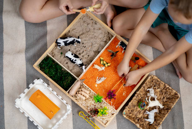 istock Touch drawer with rainbow rice inside. Children hand touch the texture. Montessori material concept for toddlers. 1351603778