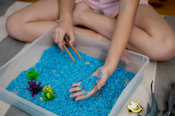 Touch drawer with rainbow rice inside. Children touch the texture with their hand. Montessori material concept for toddlers. Figurine marine life.