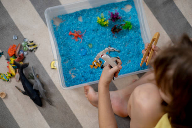 istock Touch drawer with rainbow rice inside. Children touch the texture. Montessori material concept for toddlers. 1351606889