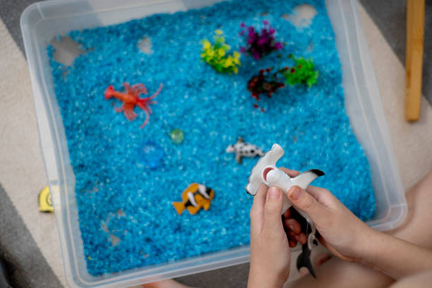 istock Touch drawer with rainbow rice inside. Children touch the texture. Montessori material concept for toddlers. 1351606891