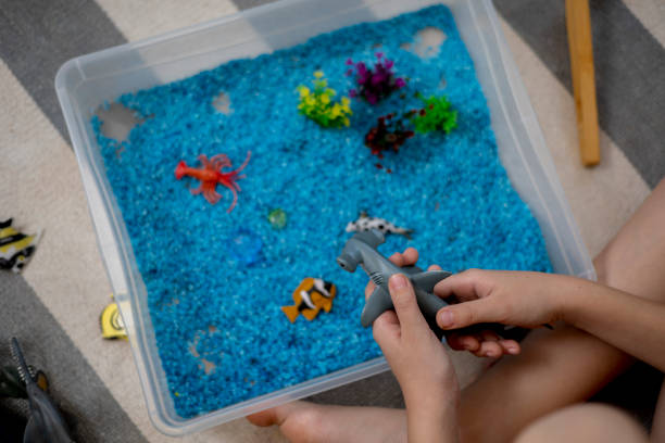 istock Touch drawer with rainbow rice inside. Children touch the texture. Montessori material concept for toddlers. 1351606894