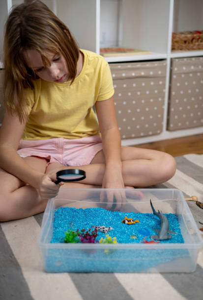istock Touch drawer with rainbow rice inside. Look through a magnifying glass. Montessori material concept for toddlers. 1351607466