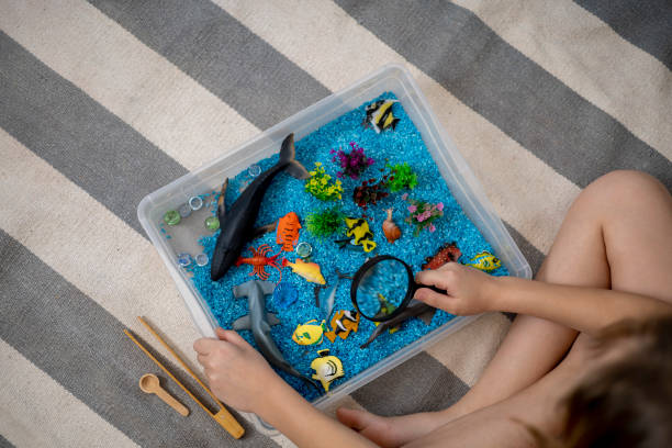 istock Touch drawer with rainbow rice inside. Look through a magnifying glass. Montessori material concept for toddlers. 1351607554