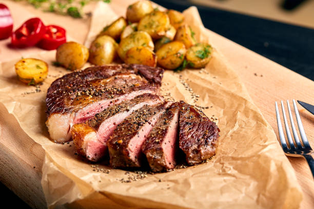 tasty and fresh, very juicy ribeye steak from marbled beef on a wooden table with baby potatoes - top sirloin imagens e fotografias de stock