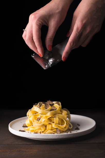 tagliatelle pasta with black truffle. female hands grating  black truffle. italian autumn pasta  recipe, rustic style - truffle tuber melanosporum mushroom 個照片及圖片檔