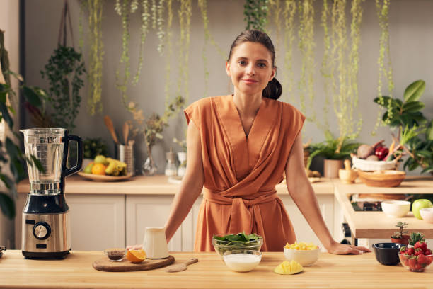 istock Happy young female looking at you before cooking smoothie 1351622014