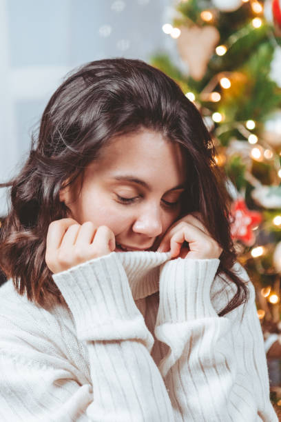 istock woman in white sweater posing near christmas tree 1351622788