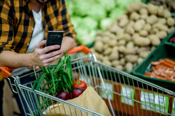 istock Young handsome man in a supermarket using smartphone while grocery shopping 1351623900