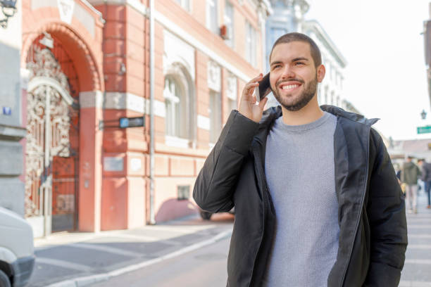 istock Smiling young man having phone conversation on a walk 1351624995