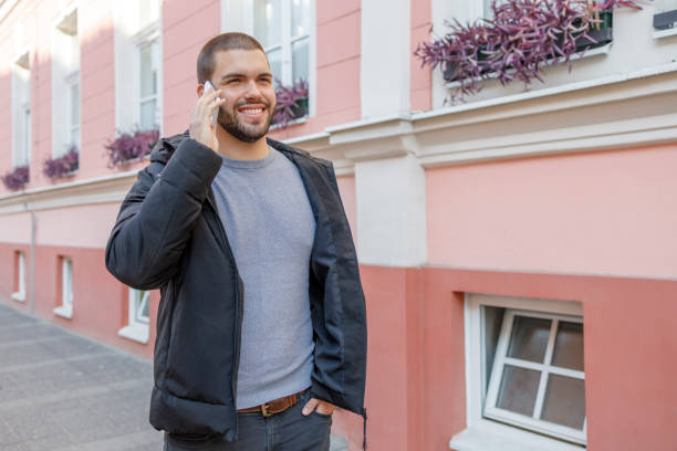 istock Cheerful young man smiling when talking via mobile phone outdoors 1351628135