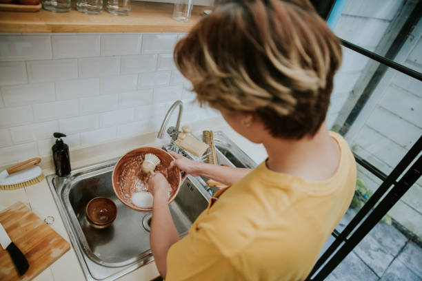 one lgbtqia person cleaning wooden dishes with eco dish brush beside his friend at home-stock photo - 洗碗刷 個照片及圖片檔