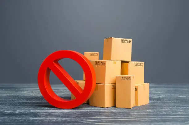 Photo of Cardboard boxes and red prohibition symbol NO. Restriction on import, ban on export of dual-use goods to countries under sanctions. Out of stock. Embargo trade wars. Overproduction or scarcity.