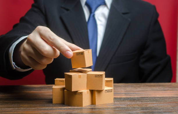 istock A businessman is building a stack of cardboard boxes. Business management, problem solving support. Production of goods and products, welfare. Distribution delivery. Logistics and warehousing. 1351631132