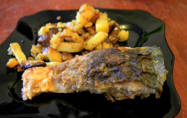istock Fried potato and roasted fish on the black plate 1351634097