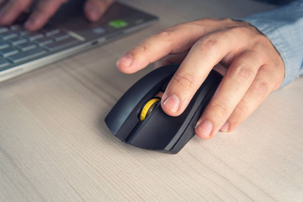 istock Businessman wearing elegant suit and using computer mouse in closeup at desk in office. Making money online. money on clicks. Advertising on Internet. 1351635088