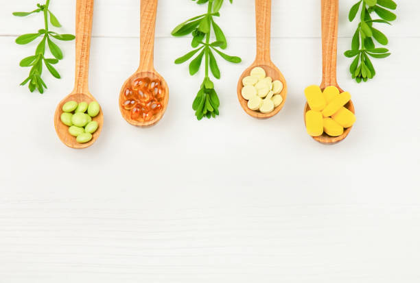 capsules and pills in wooden spoons on white wooden background - perscription capsule frame pill imagens e fotografias de stock