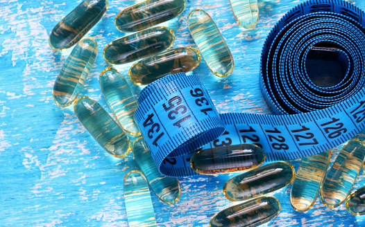 pills and measuring tape on blue background