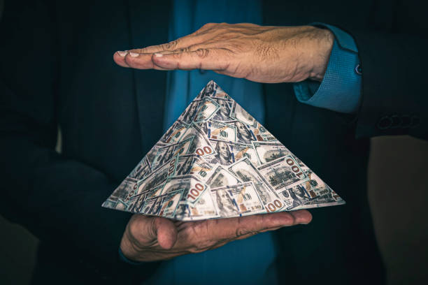 pyramid scheme in the hands of a fraudster. The concept of exchange in financial markets is the collapse of the financial system of capitalism. a pyramid scheme in the hands of a fraudster. The concept of exchange in financial markets is the collapse of the financial system of capitalism. conspiracy stock pictures, royalty-free photos & images