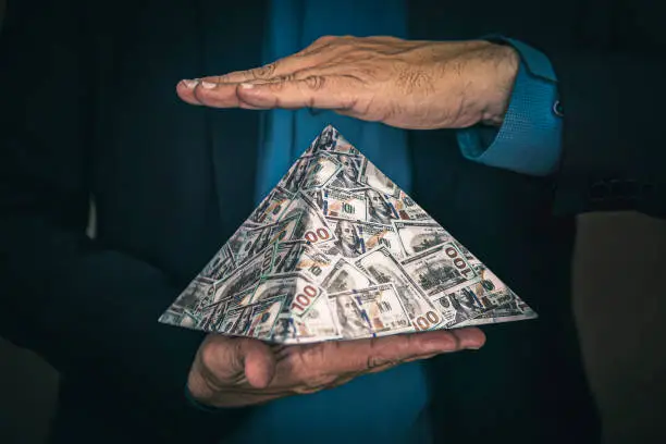Photo of pyramid scheme in the hands of a fraudster. The concept of exchange in financial markets is the collapse of the financial system of capitalism.
