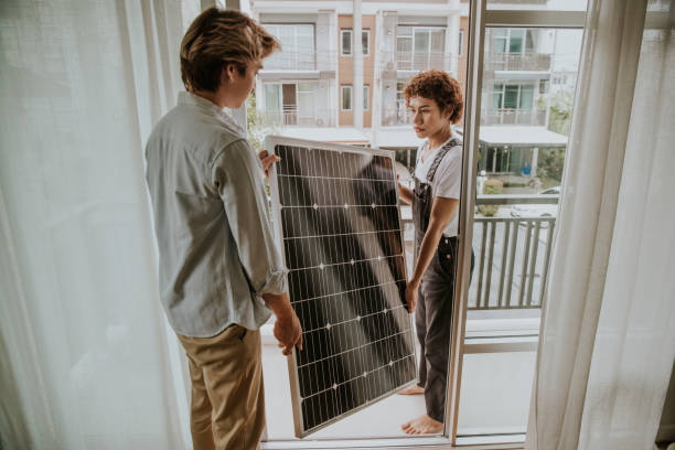 asian gay couple are installing solar panel on the balcony of the house-stock photo - energiecentrale stockfoto's en -beelden